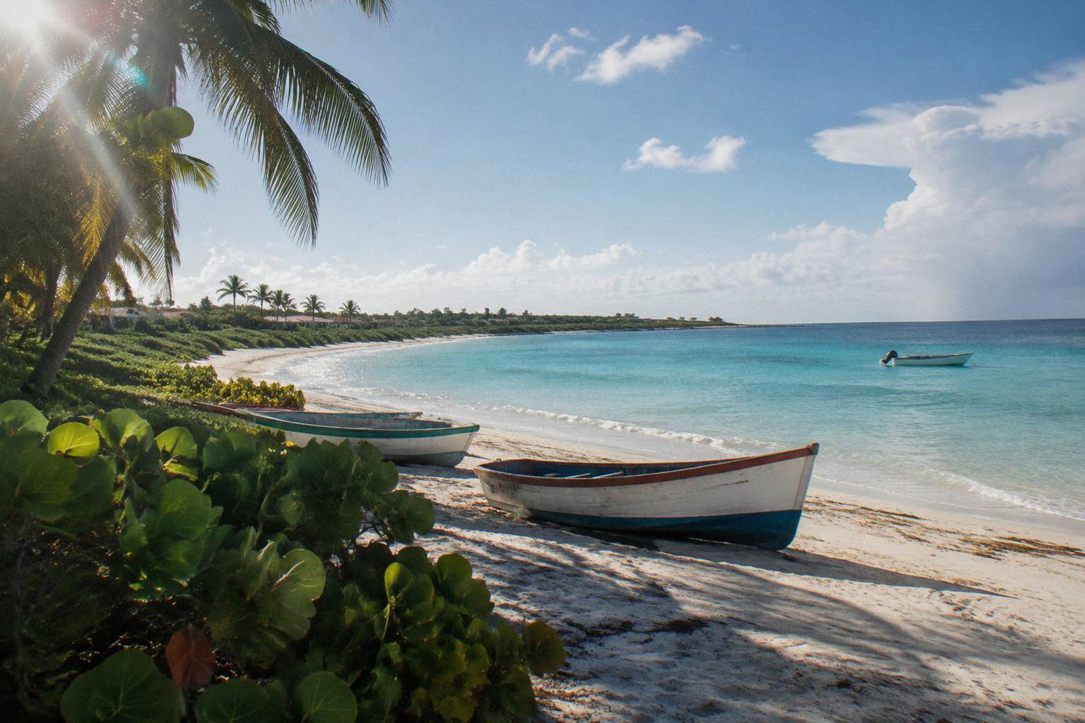 Long white beach and clear shallow water with a small boat offshore